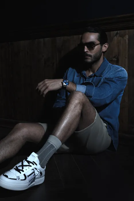 A guest seated, checking the time on his watch